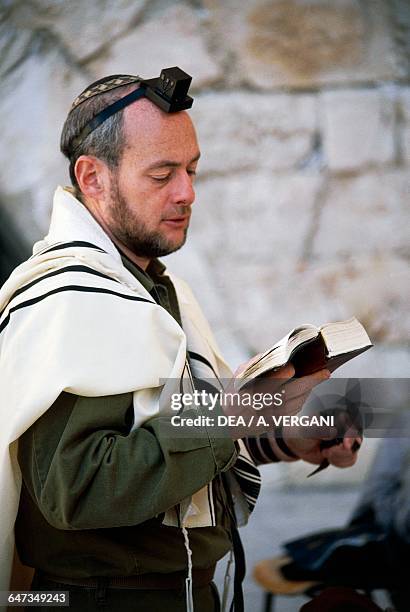 Faithful reading a prayer book in front of the Wailing Wall, Jerusalem, Israel.