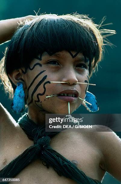 Yanomami girl with fine palm sticks through her face, traditional symbols of beauty, The Amazon rainforest, Venezuela.