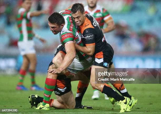 Sam Burgess of the Rabbitohs is tackled by Luke Brooks of the Tigers during the round one NRL match between the South Sydney Rabbitohs and the Wests...