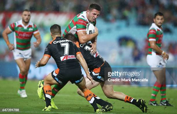 Sam Burgess of the Rabbitohs is tackled during the round one NRL match between the South Sydney Rabbitohs and the Wests Tigers at ANZ Stadium on...
