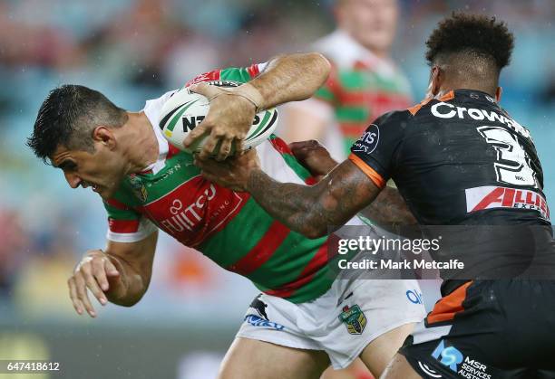 Bryson Goodwin of the Rabbitohs is tackled by Kevin Naiqama of the Tigers during the round one NRL match between the South Sydney Rabbitohs and the...