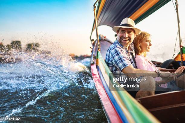 middle-aged man and his companion handsome blond lady on a boat ride in bangkok - tour boat stock pictures, royalty-free photos & images