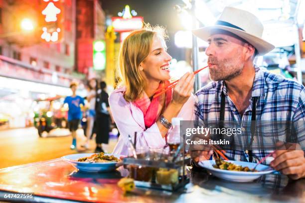 mann mittleren alters und seine begleiter hübsche blonde lady in bangkok chinatown - daily life in bangkok stock-fotos und bilder