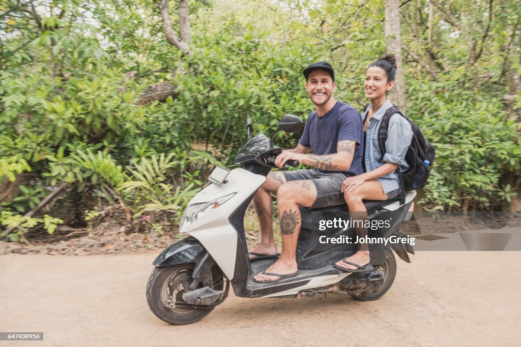 Portrait of couple sitting on moped with backpack