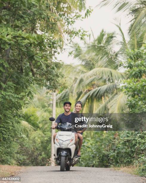 mediados de adultos par montar un ciclomotor con palmeras - holiday scooter fotografías e imágenes de stock