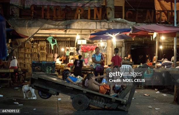 Children play on a wooden cart in Divisoria market in Manila on March 3, 2017. / AFP PHOTO / Noel CELIS