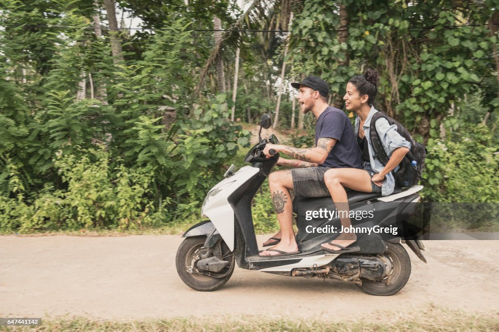 Mitte erwachsenes paar Reiten Moped durch Wald, Seitenansicht