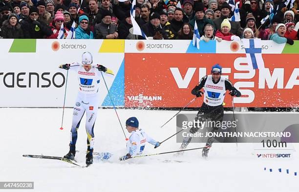 Finland's Matti Hekkinen falls next to Sweden's Calle Halfvarsson and Switzerland's Curdin Perl in the finish area of the men's cross-country 4x10 km...