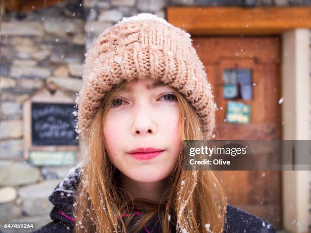 young girl under snow with knit cap - une seule petite fille stockfoto's en -beelden