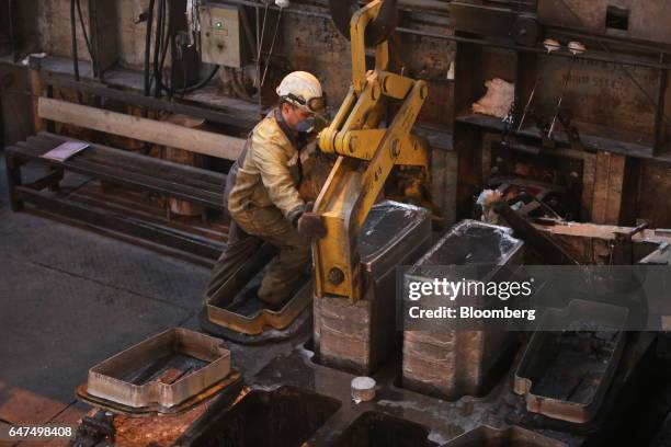 Worker positions a crane arms on an aluminum ingot in the foundry at the Krasnoyarsk aluminum smelter, operated by United Co. Rusal, in Krasnoyarsk,...