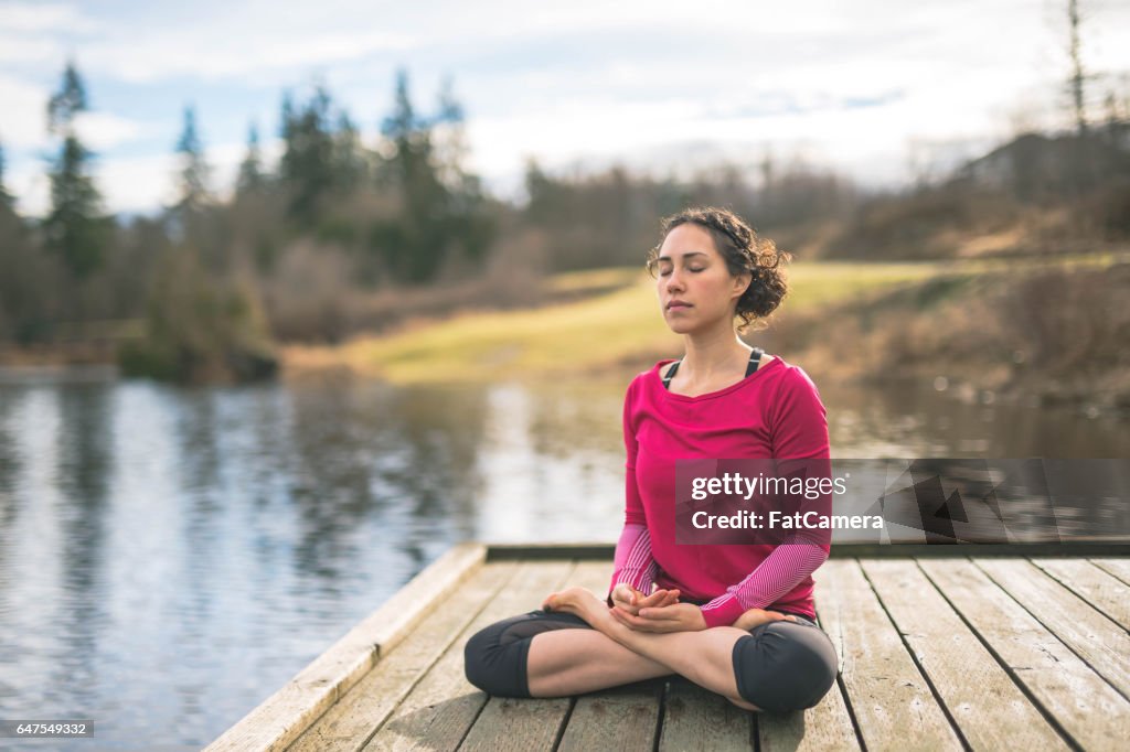 Giovane mamma che fa yoga fuori in riva al lago