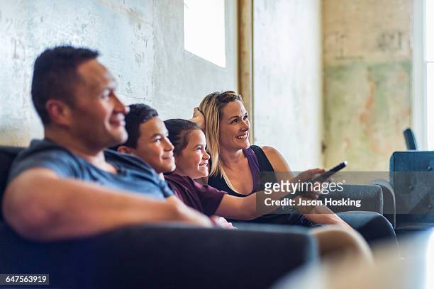 family sitting together watching tv - familie fernsehen stock-fotos und bilder
