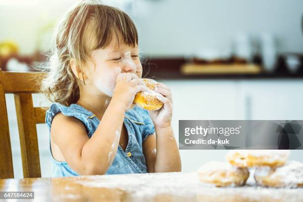 ragazza felice che mangia una deliziosa ciambella - eating donuts foto e immagini stock