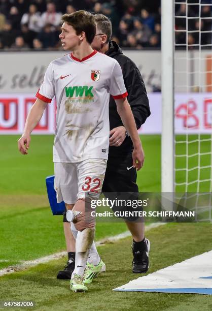 Injured Augsburg's German defender Raphael Framberger walks off with an ice pack taped to his knee during the German first division Bundesliga...