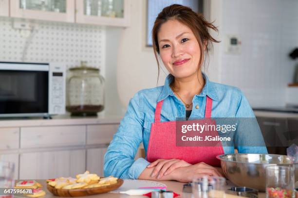 retrato de una mujer de hornear galletas en casa - decorar una tarta fotografías e imágenes de stock
