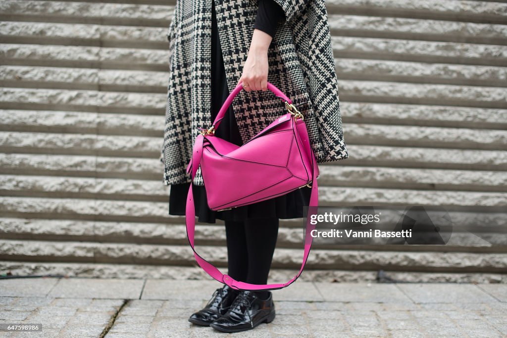 A guest poses with a Loewe puzzle bag after the Undercover show at News  Photo - Getty Images