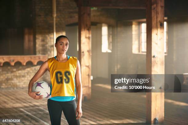 portrait of young woman with netball in gym. - startnummer stock-fotos und bilder