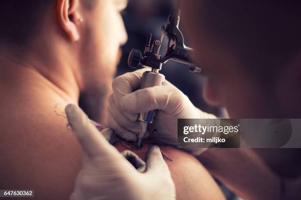 tattooing in tattoo studio - tattoo shoulder stock pictures, royalty-free photos & images