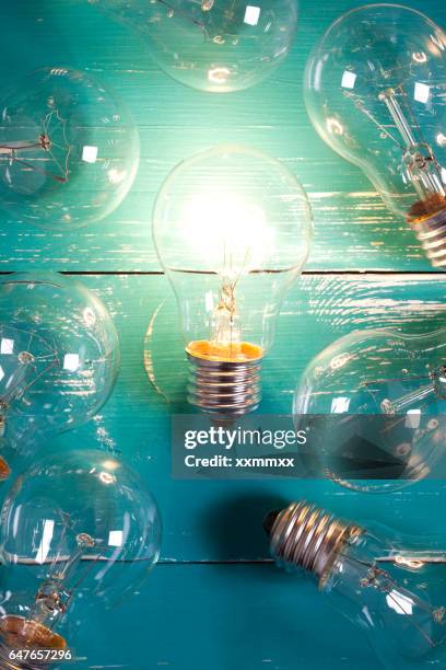 vintage incandescent bulbs on turquoise wooden table - incandescent bulb stock pictures, royalty-free photos & images