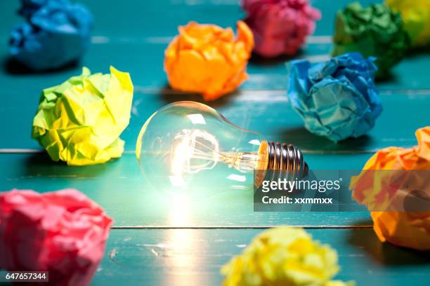 bombilla incandescente y coloridas notas sobre mesa de madera turquesa - creatividad fotografías e imágenes de stock
