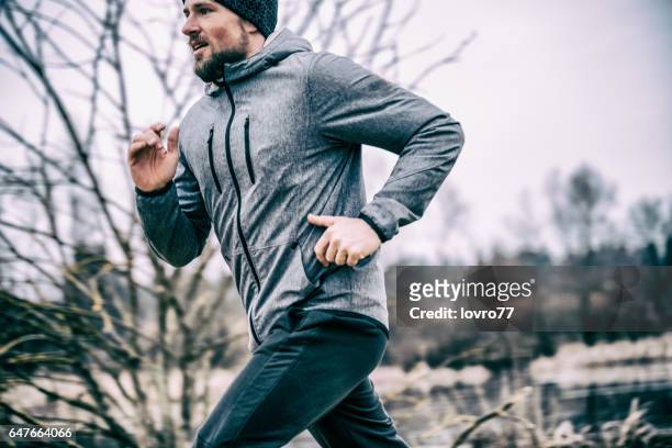 junger mann läuft auf dem feld - winter sport stock-fotos und bilder