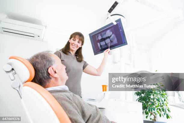 eine zahnärztin behandelt einen patienten - dental imaging stock pictures, royalty-free photos & images