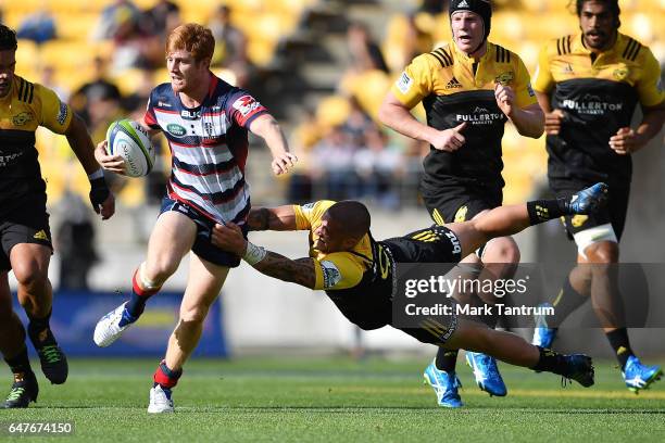 Nic Stirzaker of the Melbourne Rebels is tackled by TJ Perenara of the Hurricanes during the round two Super Rugby match between the Hurricanes and...