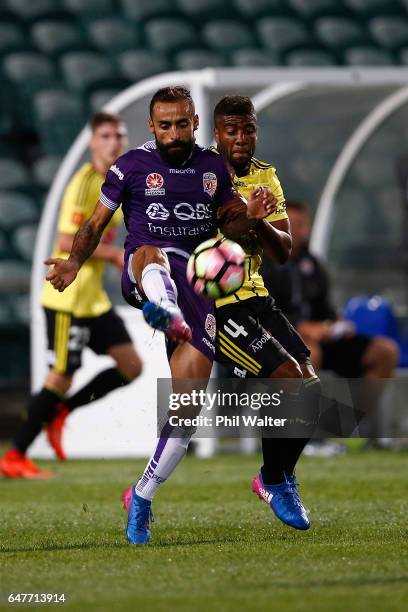 Diego Castro of Perth kicks under pressure from Rolieny Bonevacia of Wellington during the round 22 A-League match between the Wellington Phoenix and...