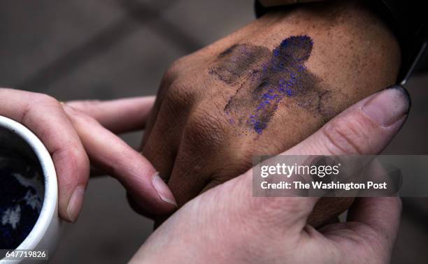 Pastor Robin Anderson, gives "glitter ashes" to Tonya Matthews, for Ash Wednesday, outside the Braddock Road metro station, in Alexandria, VA, March...