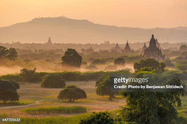pagodas and the mist at sunset in bagan, mandalay, myanmar - bagan temples damaged in myanmar earthquake stock pictures, royalty-free photos & images