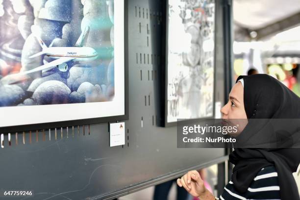 Family member of passengers onboard the missing Malaysia Airlines flight MH370 watch art work during a remembrance event for Malaysian Airlines MH370...