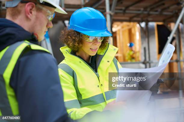 contremaître de construction femelle instruisant un travailleur. - géomètre photos et images de collection