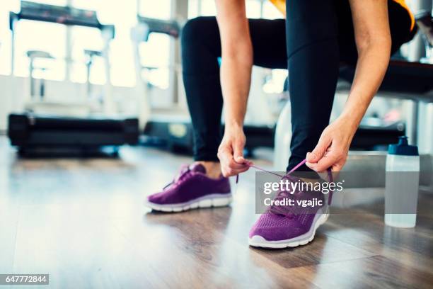 mature woman tying sports shoe in the gym - unrecognizable person stock pictures, royalty-free photos & images