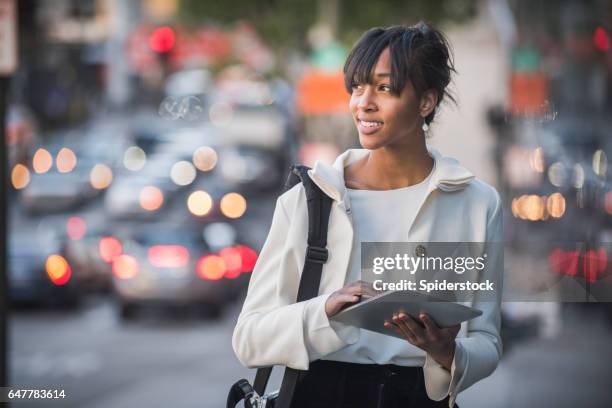 un millénaire femelle afro-américaine en tenue professionnelle avec un appareil mobile, marchant dans les rues du centre ville de los angeles - indépendance photos et images de collection