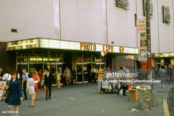 View of people walking outside of the New York Coliseum convention center, at Columbus Circle and 58th Street, on the west side of Manhattan, New...