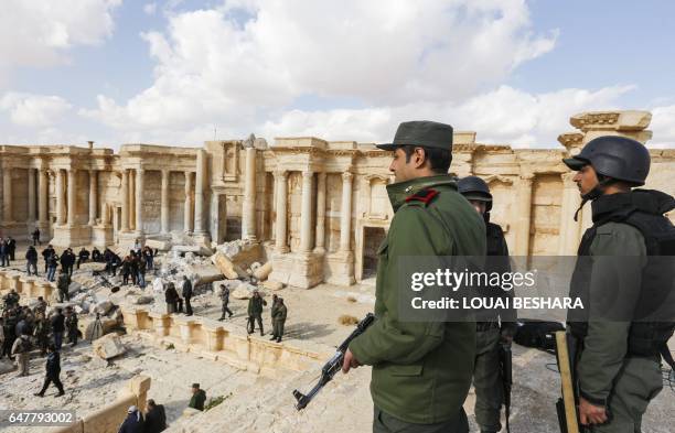 Picture taken on March 4, 2017 shows Syrian soldiers standing guard at the site of the damaged Roman amphitheatre in the ancient city of Palmyra in...