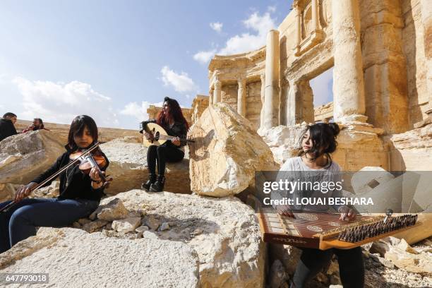 Syrian musicians play at the site of the damaged Roman amphitheatre in the ancient city of Palmyra in central Syria, during a tour organised by the...