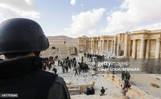 Picture taken on March 4, 2017 shows Syrian soldiers standing guard at the site of the damaged Roman amphitheatre in the ancient city of Palmyra in...