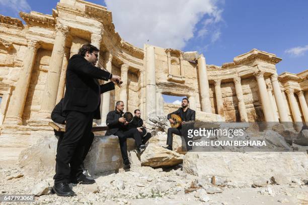 Syrian musicians play at the site of the damaged Roman amphitheatre in the ancient city of Palmyra in central Syria, during a tour organised by the...