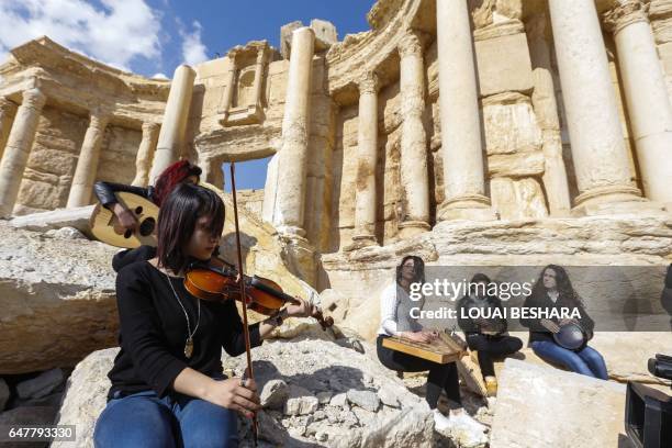 Syrian musicians play at the site of the damaged Roman amphitheatre in the ancient city of Palmyra in central Syria, during a tour organised by the...