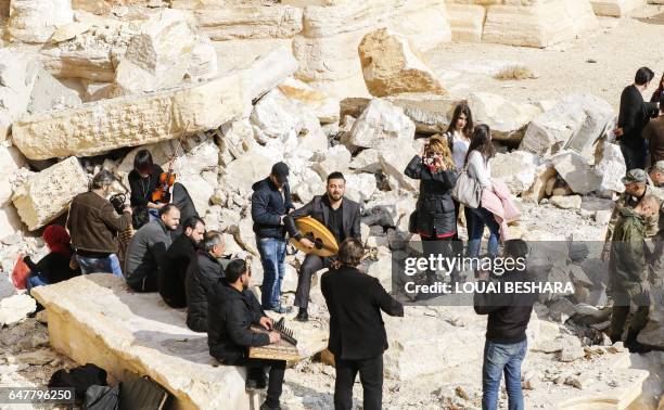 Syrian musicians play at the site of the damaged Roman amphitheatre in the ancient city of Palmyra in central Syria, during a tour organised by the...