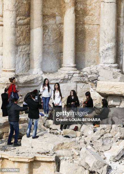 Syrian musicians play at the site of the damaged Roman amphitheatre in the ancient city of Palmyra in central Syria, during a tour organised by the...