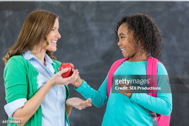 écolière mignon donne enseignant une pomme - kids play apple photos et images de collection