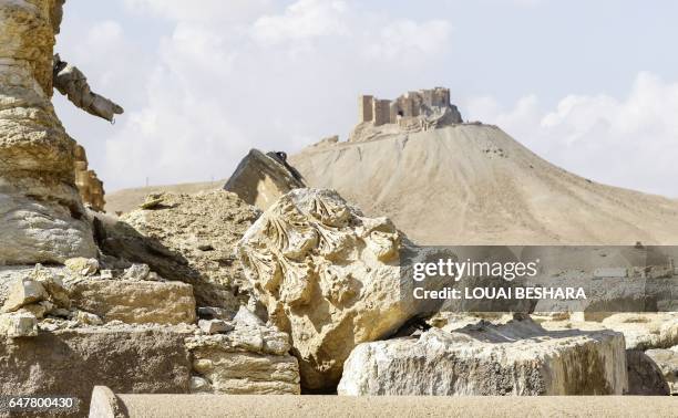 Picture taken on March 4, 2017 shows a fallen column capital at the site of the ancient city of Plamyra in central Syria, with the Fakhr-al-Din...