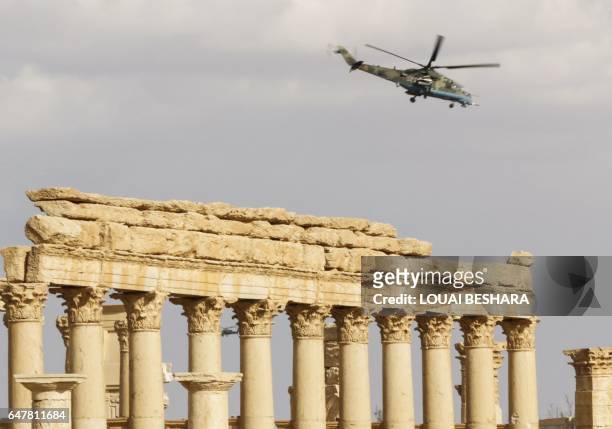 Picture taken on March 4, 2017 shows a Russian Mil Mi-24 "Hind" attack helicopter flying above the damaged site of the ancient city of Palmyra in...