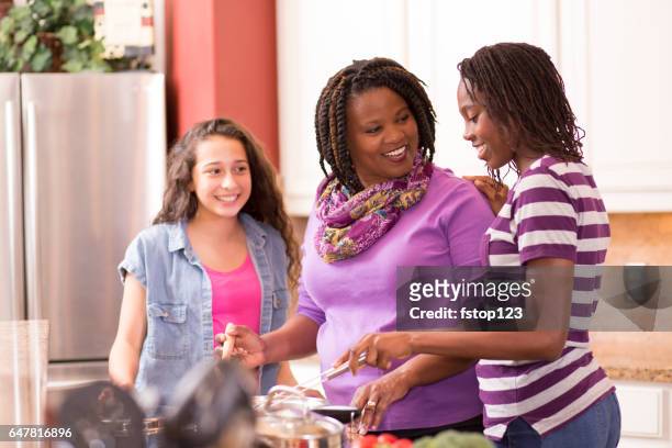 multi-ethnic family at home cooking together in kitchen. - foster care stock pictures, royalty-free photos & images