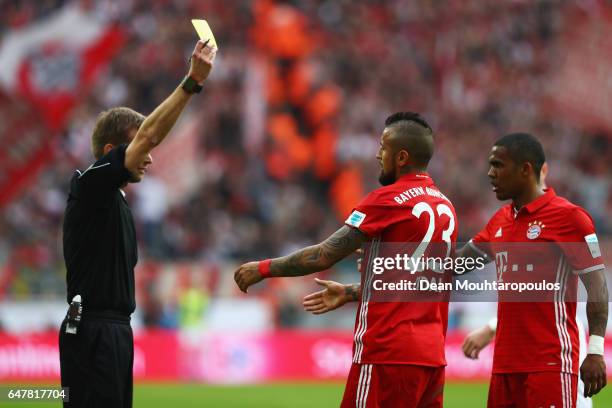 Referee, Jochen Drees shows Arturo Vidal of Bayern Munich a yeloow card during the Bundesliga match between 1. FC Koeln and Bayern Muenchen at...