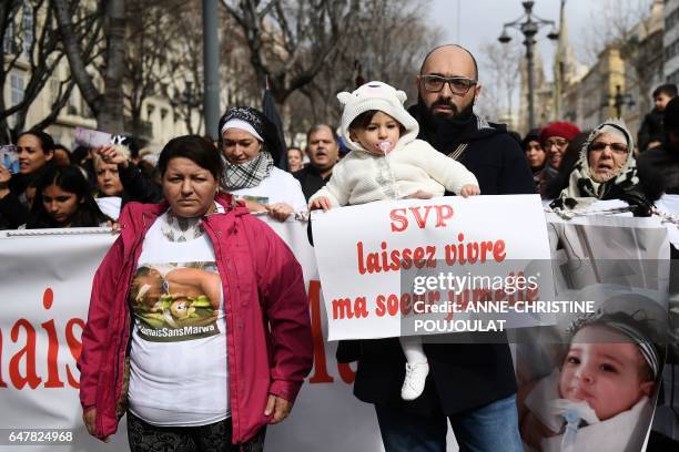 Mohamed Bouchenafa, , father of Marwa, his 15-month-old heavily handicapped daughter, holds Safa, his daughter and Marwa's twin sister and a sign...