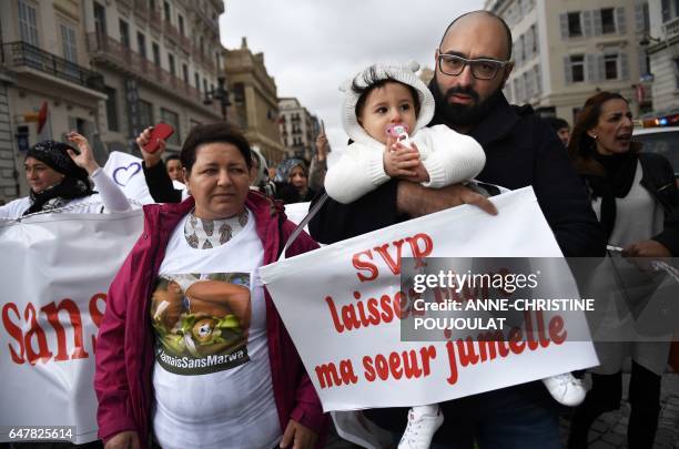 Mohamed Bouchenafa, , father of Marwa, his 15-month-old heavily handicapped daughter, holds Safa, his daughter and Marwa's twin sister and a sign...