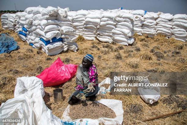 Woman collects grains left on the ground after a food distribution on March 4 in Ganyiel, Panyijiar county, in South Sudan. - South Sudan was...